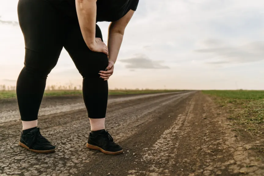 肥胖的女人在跑步期间碰到膝盖