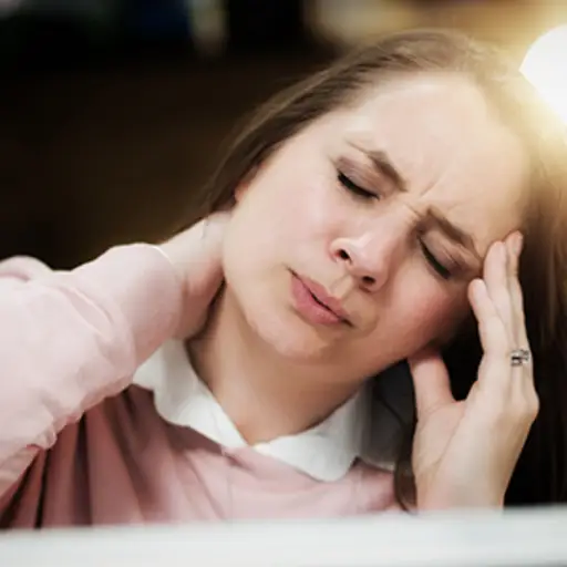 在工作的妇女从头疼和僵硬的脖子畏缩。