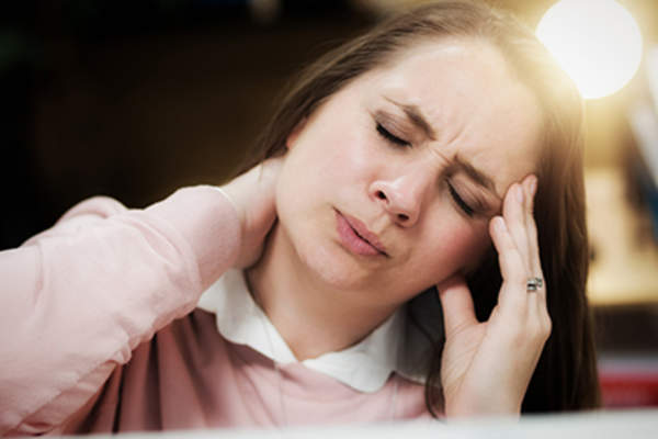 在工作中的女人头痛和颈部僵硬畏缩。