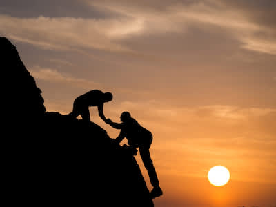 一个人帮助另一个人爬陡坡。