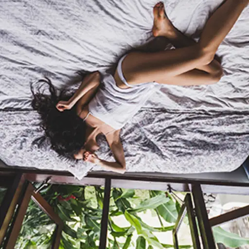Woman in white lingerie lounging in bed in the morning, upside down.