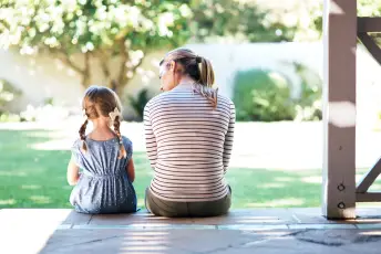 母亲向她的小女儿解释j型育儿袋。