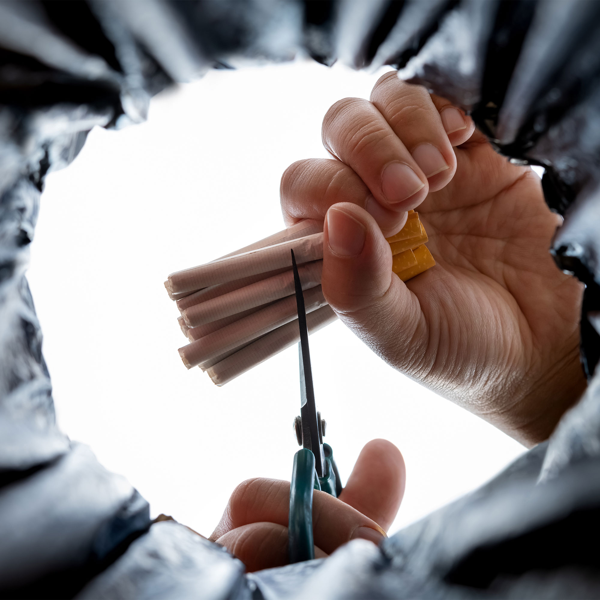 从下面看，一个男人把香烟切成两半