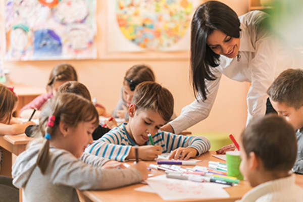 快乐的幼儿园老师帮助孩子们画画。