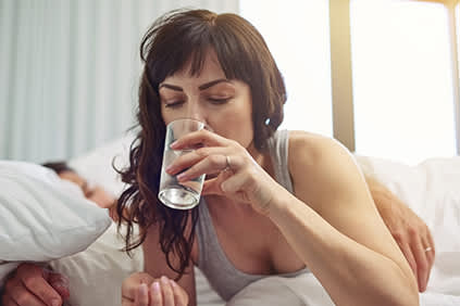 在床上喝水的女人。