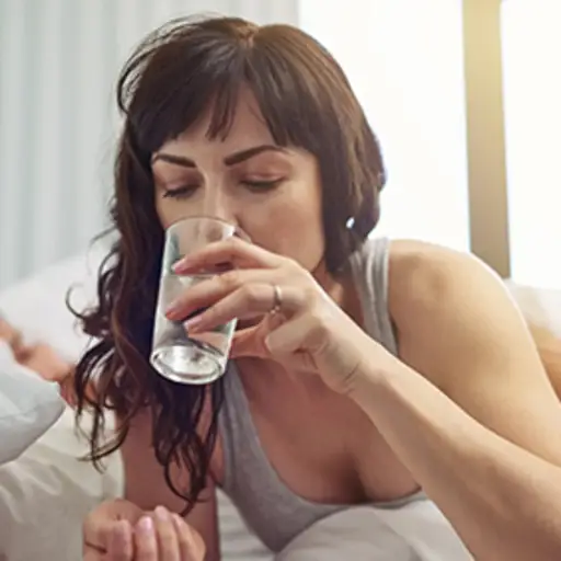 在床上喝水的女人。