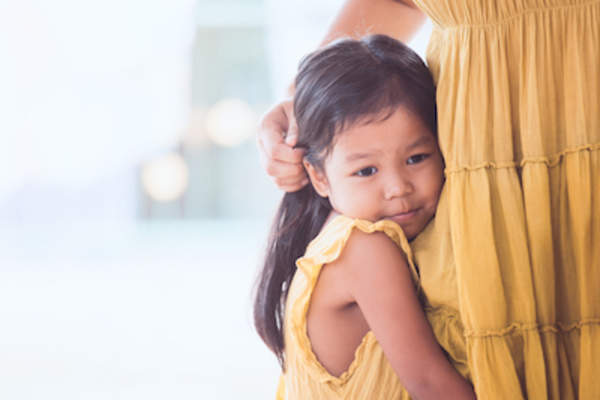 女孩抱着妈妈的腿。