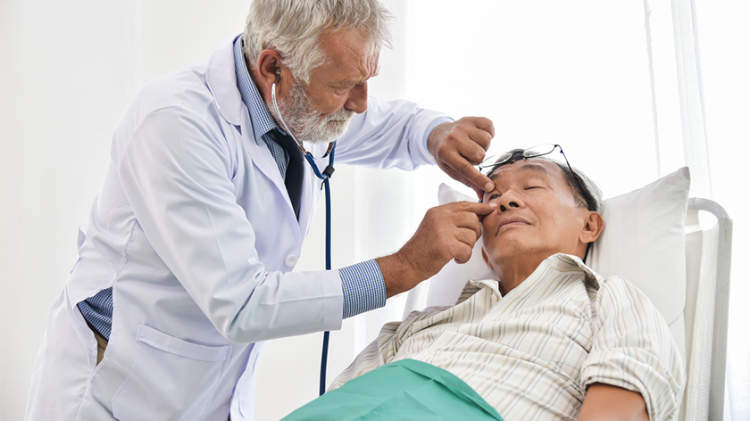 老人躺下时医生检查他的眼睛。