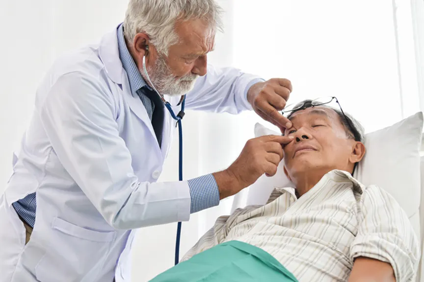 医生在老人躺下时检查他的眼睛。