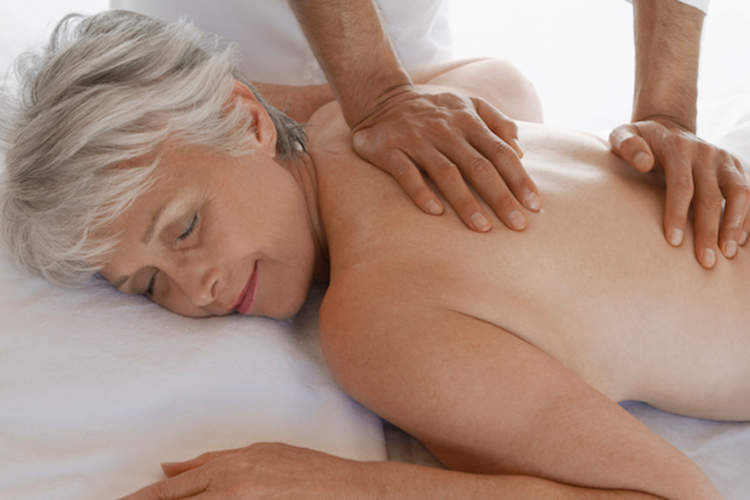 一位上了年纪的妇女因背痛而接受按摩。