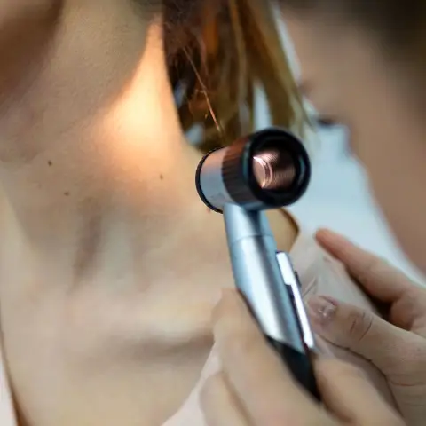 A dermatologist examines a patient’s skin