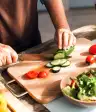 妇女在菜板上切新鲜蔬菜。