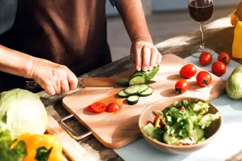 在切菜板上切新鲜蔬菜的女人。
