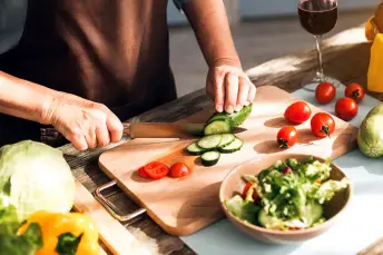 妇女在菜板上切新鲜蔬菜。