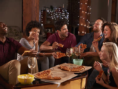 年轻人在家里的聚会上分享披萨。