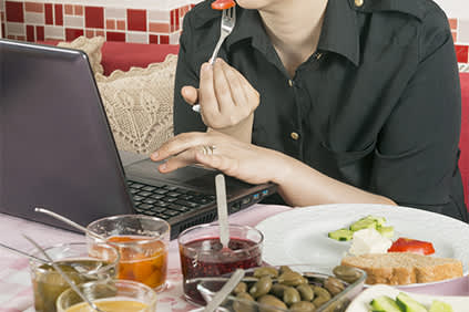 吃妇女在电脑上工作一段时间。