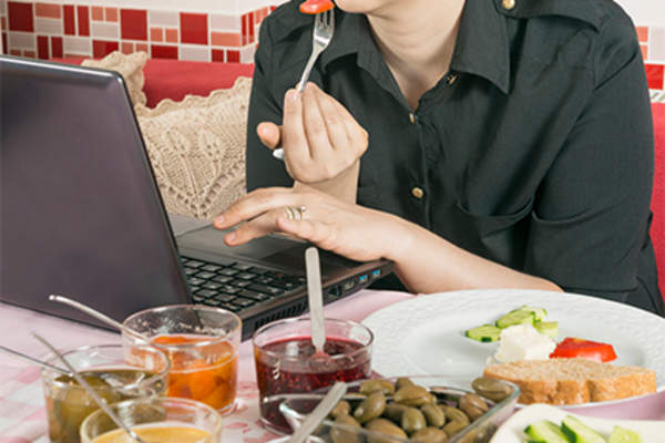 吃妇女在电脑上工作一段时间。