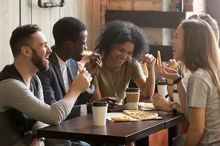 一群微笑的朋友在披萨店。