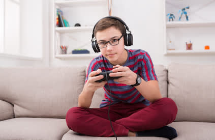 在沙发上玩电子游戏的男孩。