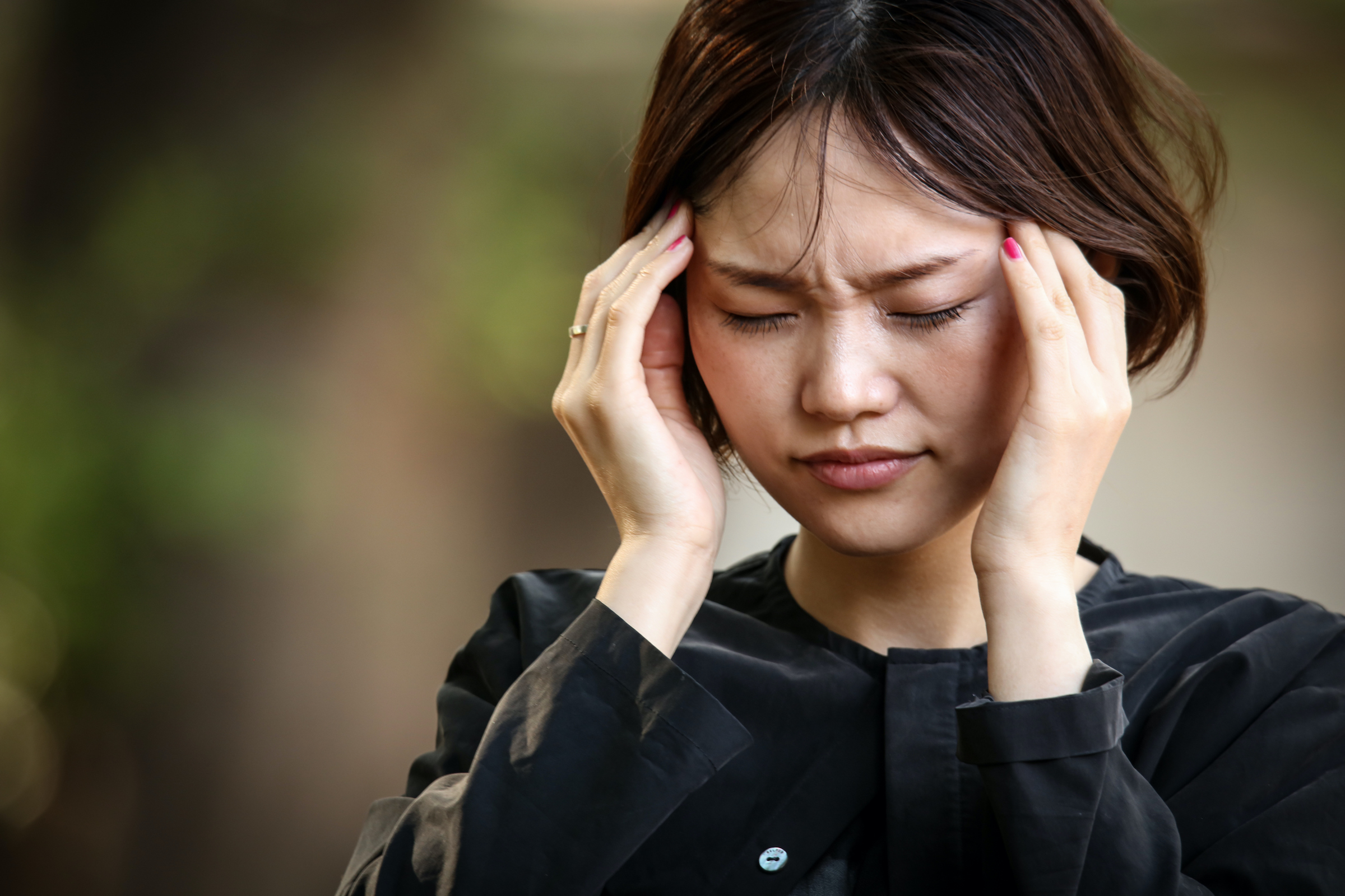 Young woman pressing temples, appearing to have a headache