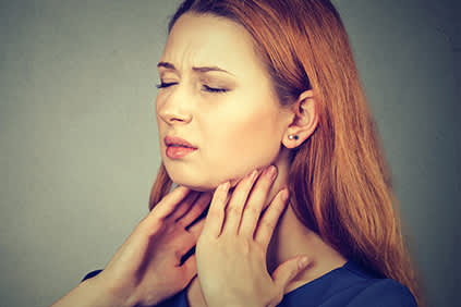 因咽喉、甲状腺或颈部疼痛而做鬼脸的妇女。