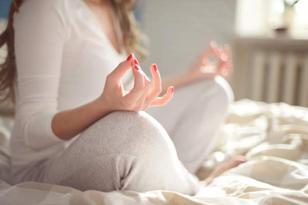 年轻女子在床上在卧室里冥想