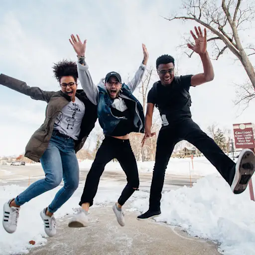 three young adults smiling and jumping