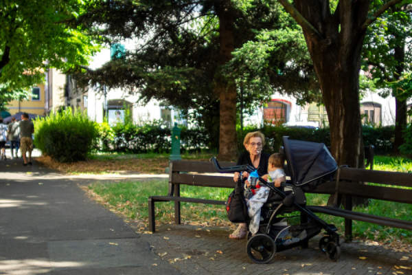 老年妇女坐在长椅上，在宝宝面前吸烟