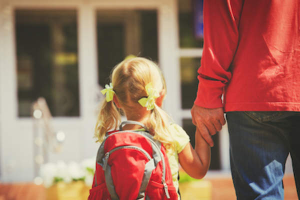 扎着马尾、背着红色背包的小女孩牵着父母的手。
