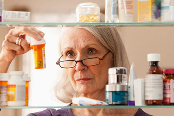 高级女子看着药柜吃药。