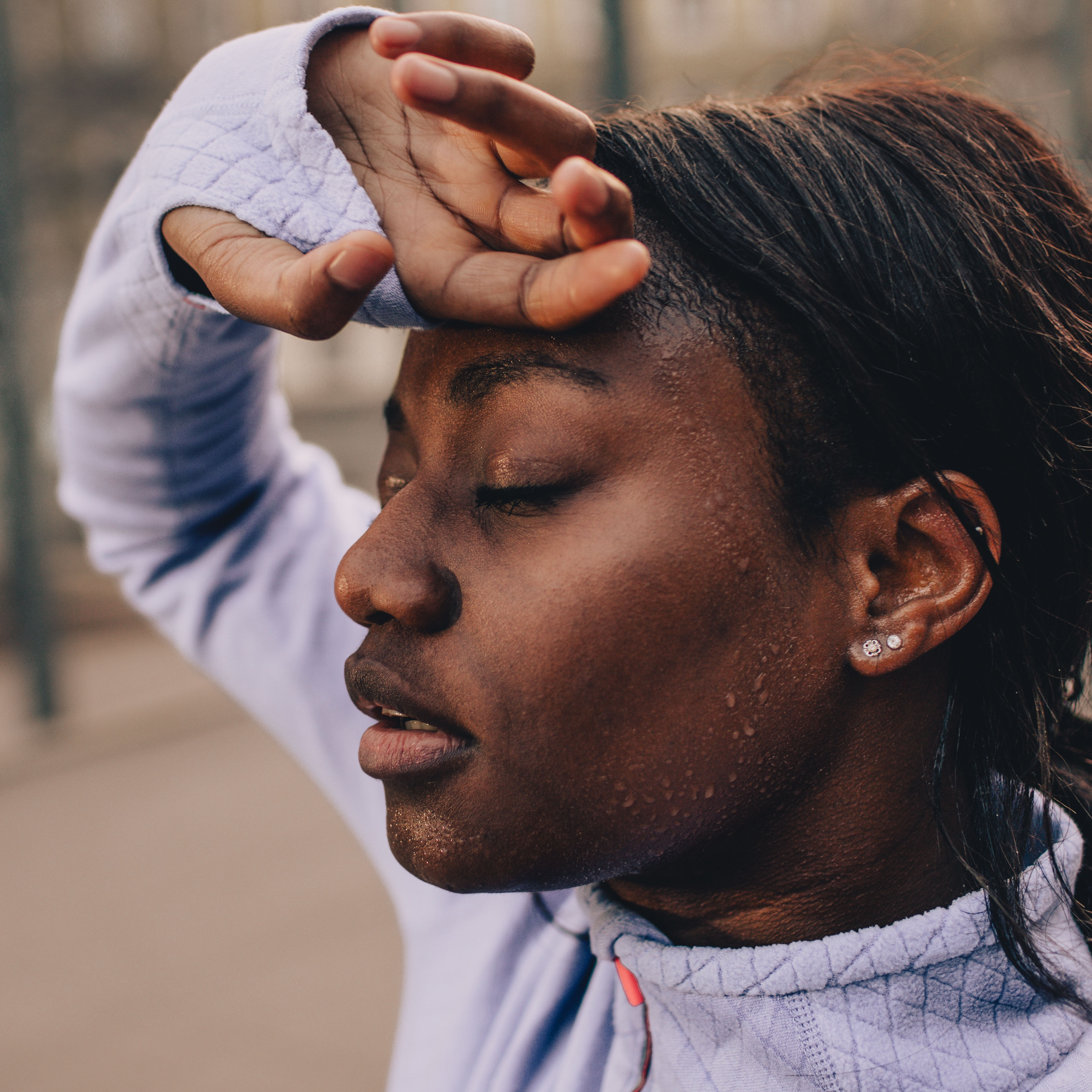 图为一名年轻女子在剧烈运动后擦去额头上的汗水