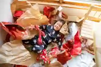 一个孩子躺在一堆礼物包装纸上