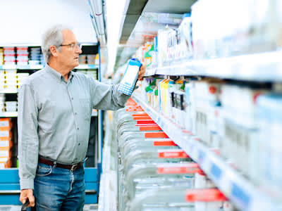 男人购物的脂肪含量的牛奶检查标签。