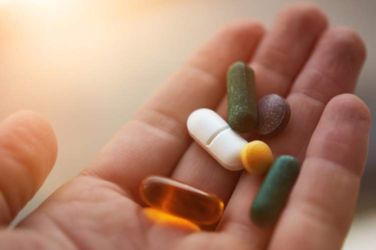 手握许多膳食补充剂药丸