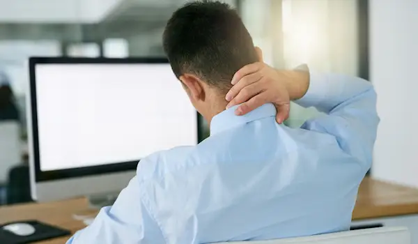 一个坐在办公桌前揉脖子的男人。