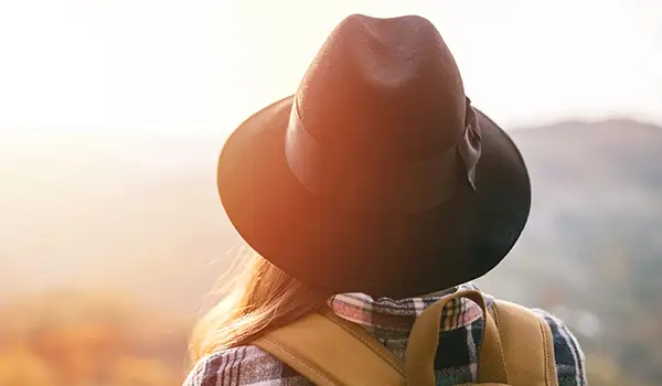 日落时戴着帽子徒步旅行的女人。