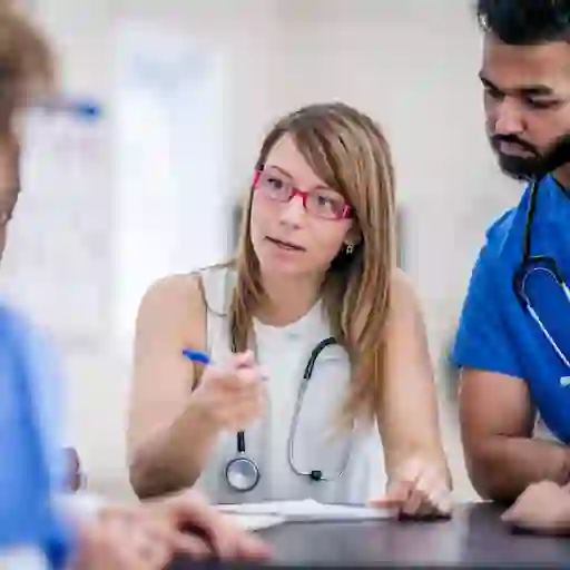 一群医护人员围在一张桌子旁讨论病人的护理。