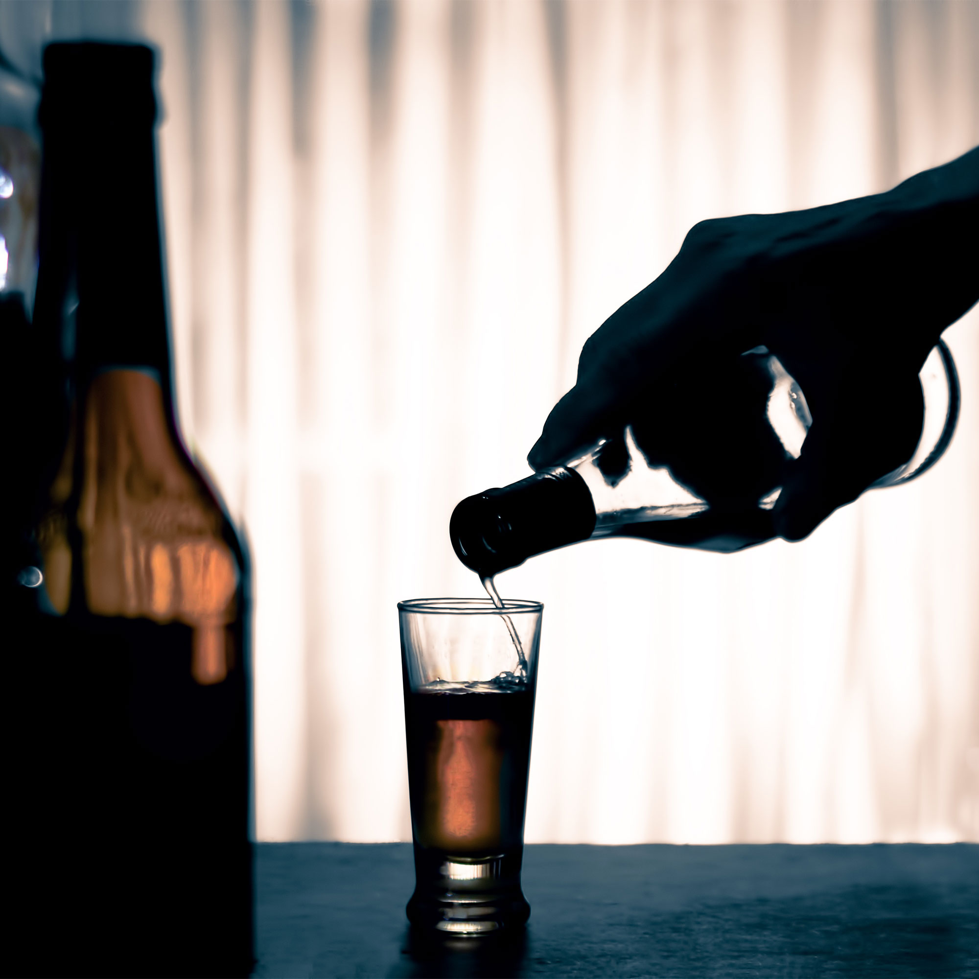 有人将酒倒入射击玻璃杯中