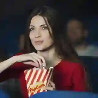 Woman at the movies eating popcorn.