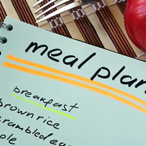 Notepad with meal plan and apple.