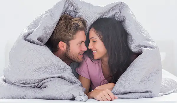 年轻夫妇在床上盖被子。
