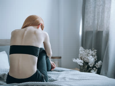 患厌食症的女人坐在床上急着睡觉，怕睡瘫。