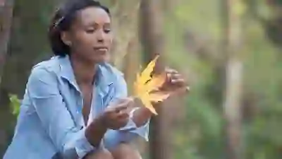 女人坐着，思考着，手里拿着一片落叶。