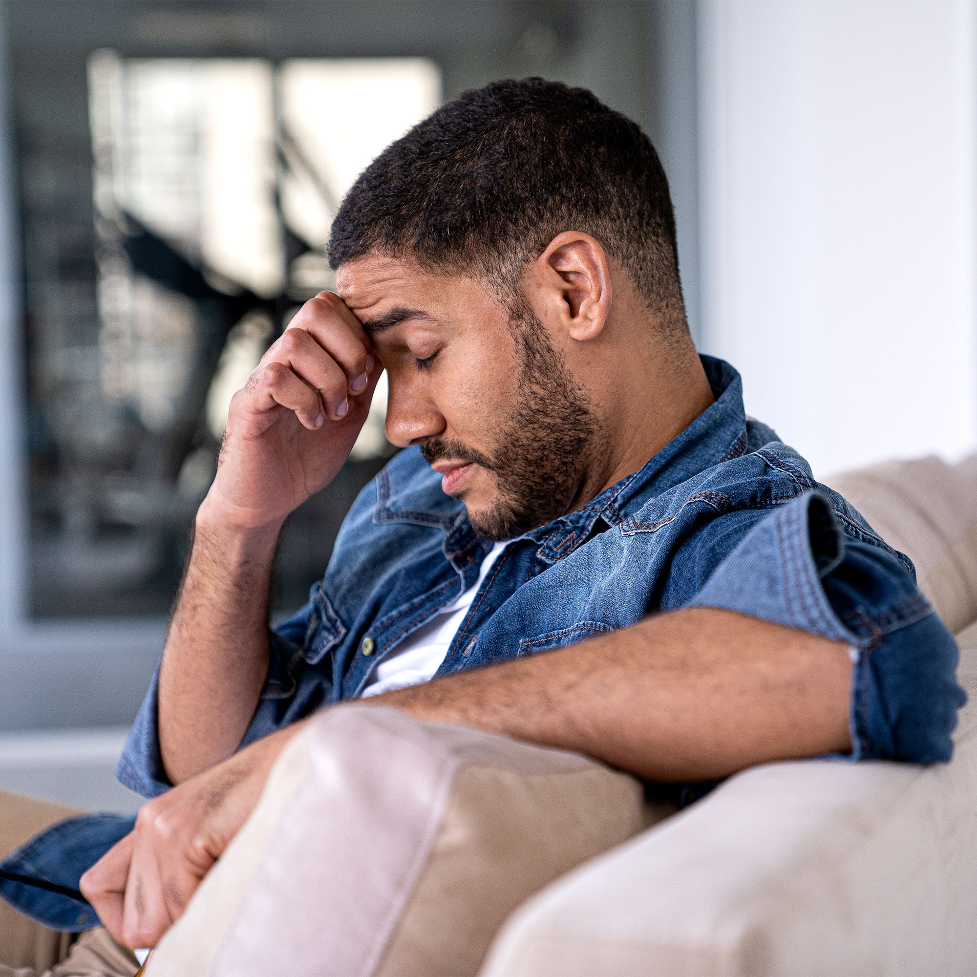 一个男人坐在一个沙发上,搓着自己的头