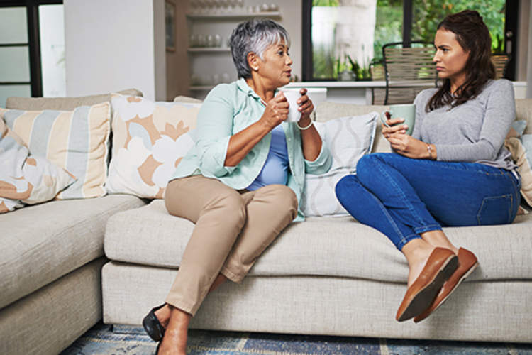 老母亲和女儿在沙发上聊天。