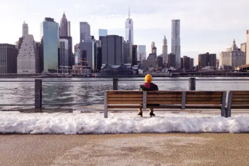人坐在长凳上被融化的雪