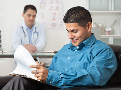 西班牙裔病人填写表格，在医生的办公室。