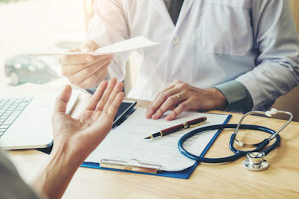 医生在他的办公室里给病人开处方。