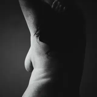 black and white image of topless woman from behind