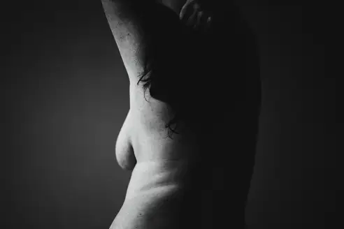 Close-up image of female body, breast isolated over grey studio